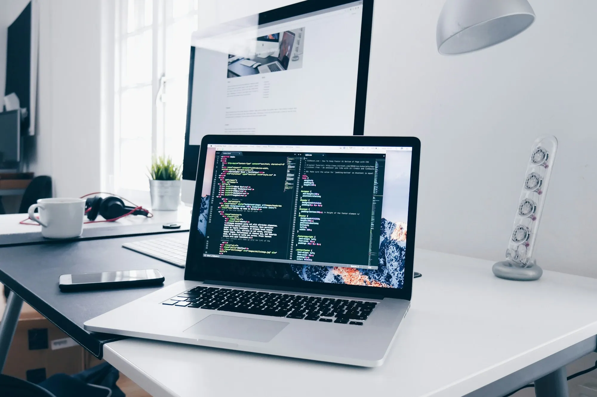 A laptop on a desk showing code in an editor